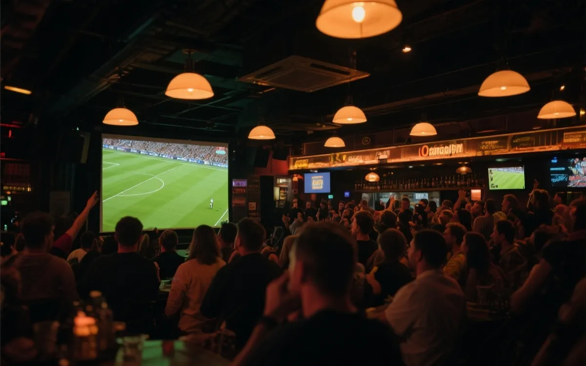 夜晚酒吧里多人观看足球比赛的大屏，氛围热烈